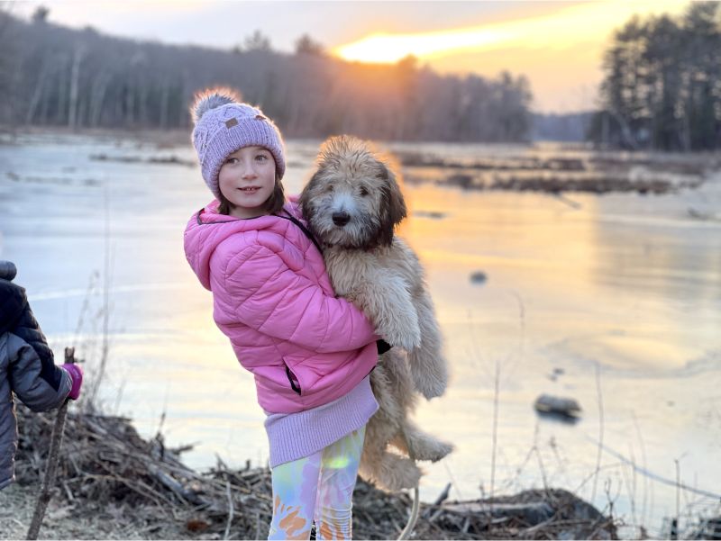 Dave's daughter holding their dog Charlie at sunset in the winter