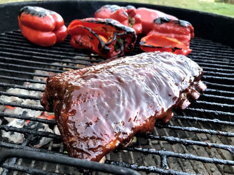 Cooking ribs and chared red peppers on the grill at a summer time BBQ